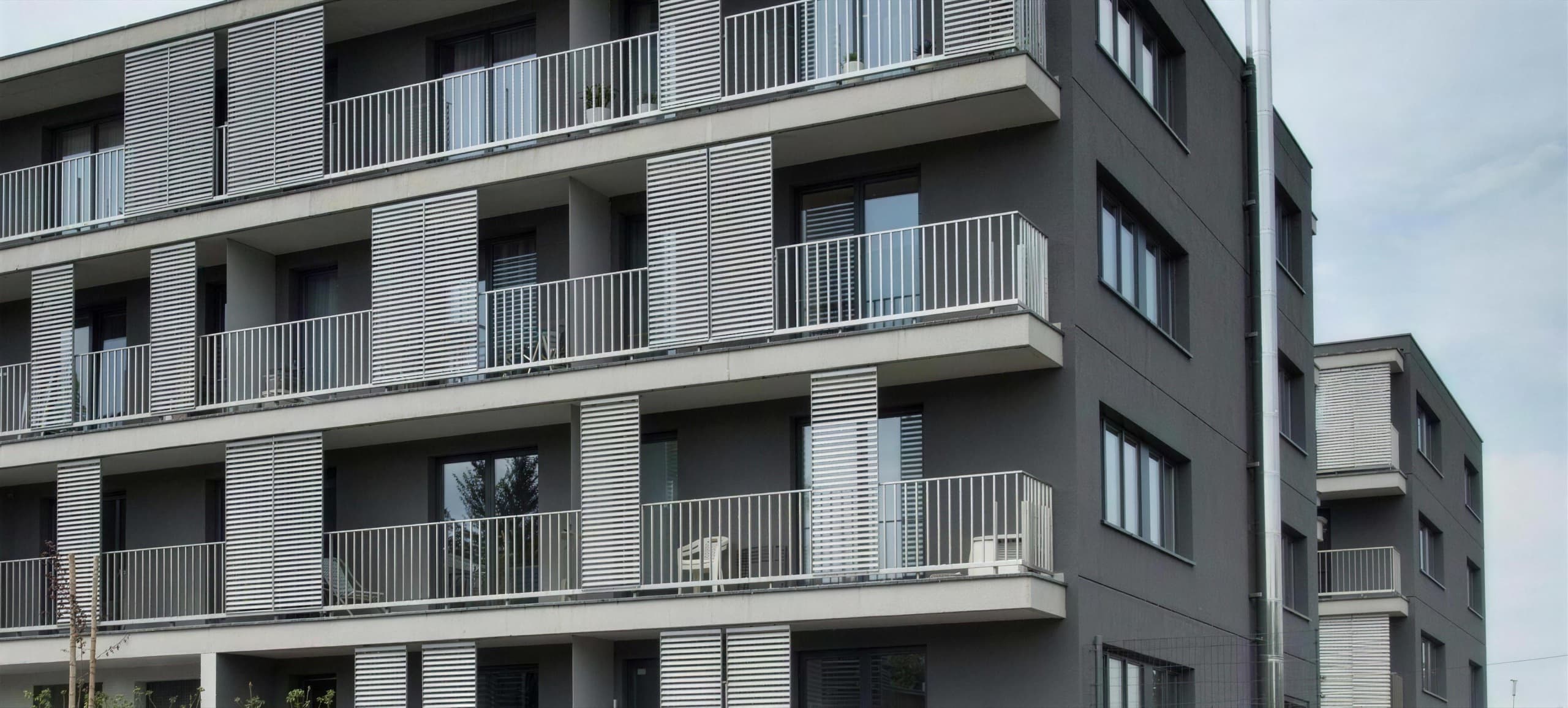 Wohnquartier Lerchenfeld — Gebäudeecke mit auskragenden Balkonen und Metall-Läden